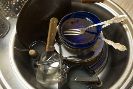 A pile of unwashed dirty dishes in the sink in the kitchen or dining room.Work at home for a...