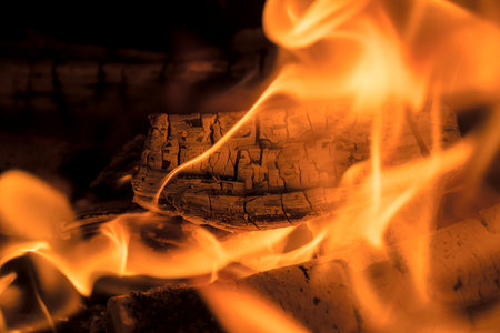 A blazing fire in the dark. Inflammation of firewood in the fire. A bright burning flames. Sparks and flames in the darkness. Red-hot heat and tongue flames. Fiery flaming bonfire.の写真素材