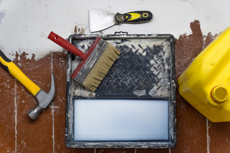 A hammer, a spatula, a paint brush, a canister and a tray for paints lie on the floor during the repair and restoration of the house.Work as a Builder or handyman in the house.Repairing a roomの写真素材