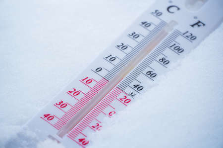 The thermometer lies on the snow in winter showing a negative temperature. Meteorological conditions in a harsh climate in winter with low air and ambient temperatures.の写真素材