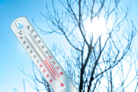 The thermometer lies on the snow and shows a negative temperature in cold weather on the blue...