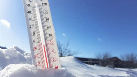 Thermometer in winter in the cold on snow and analyzes low negative air temperatures in clear sunny...
