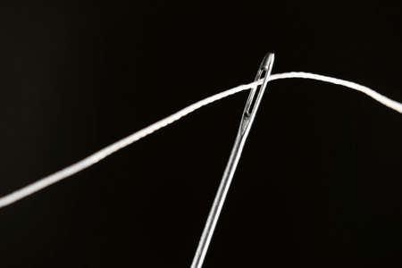 The thread is threaded through the eye of a sewing needle. Sewing and needlework classes.Workshop of...