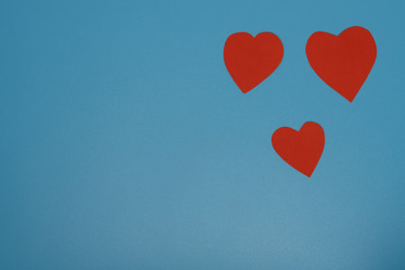Three paper red hearts lie on light grey background. Valentines Day theme. Flat lay. Copy space. Love and romantic.の写真素材