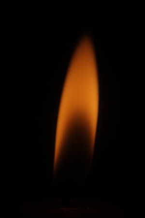 close up of a burning candle, black, red, orange, candle wick, flame, vertical photoの写真素材