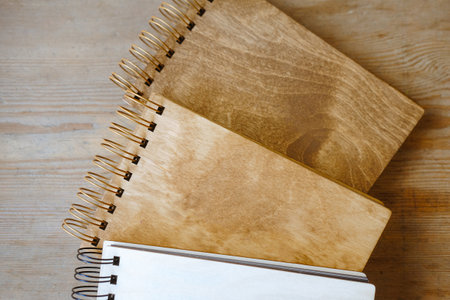 Notebooks with a wooden cover lie on the tableの写真素材