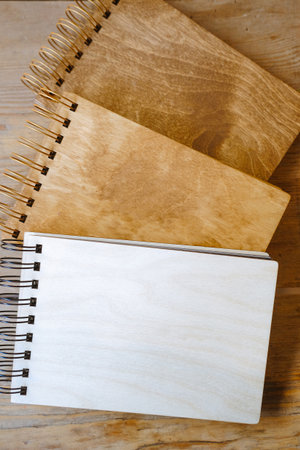 Notebooks with a wooden cover lie on the tableの写真素材