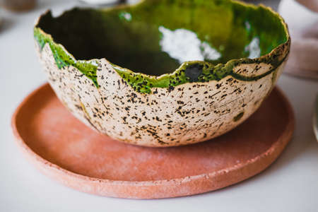 A product made of clay. Colorful kitchen items on the shelf. Handmade plate