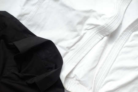 White kimono for karate training. Next to it is a black classic shirtの写真素材