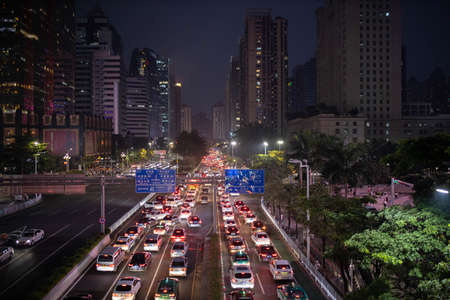 Guangzhou, China - October 12, 2019. Cars drive in the evening with headlights on on the road in the...