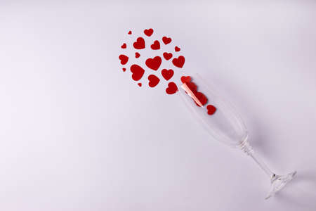 One glass with red hearts on white background. Valentine's Day, February 14, love concept. Flat lay,...