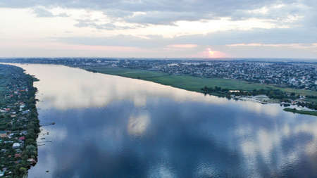 Wide river Dnieper. There is a city on one bank of the river and summer cottages on the other bank.