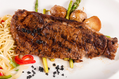 Grilled beef steaks with asparagus and pasta, black rock saltの写真素材
