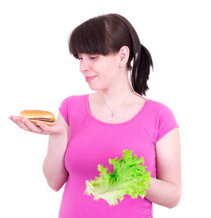 The young woman selects between a hamburger and saladの写真素材