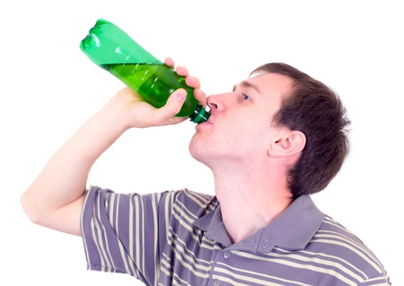 The young man drinks from a green bottleの写真素材