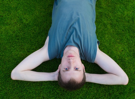 The young man lies on a green grassの写真素材