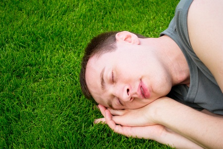the young man sleeps on a green grassの写真素材