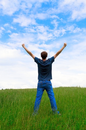 The young man on a meadow having lifted hands upwardsの写真素材