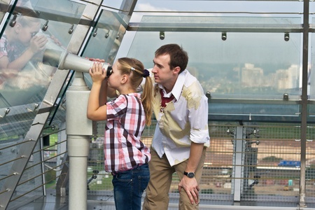Father and daughter looking through tourist telescope , exploring landscape.の写真素材