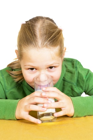 Happy little girl with a glass of milk, isolated over whiteの写真素材