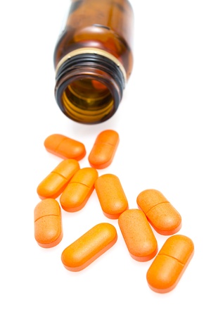 Pills spilling out of pill bottle isolated on whiteの写真素材