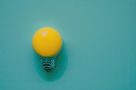 flat lay photo of yellow bulb on turquoise blue background. Illustration Generative AIの素材
