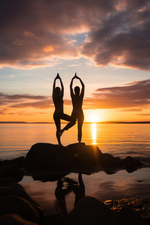 A dynamic photo of a group of people practicing yoga on a beach at sunsetの素材