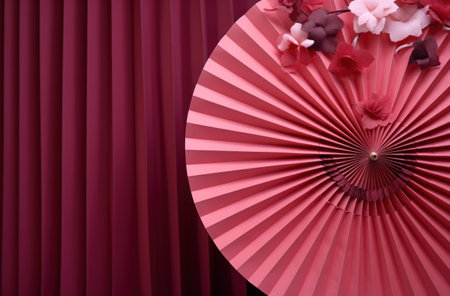 a red fan is hung from a pink wall.の素材