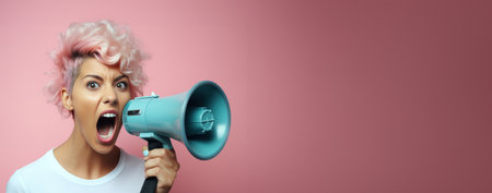 young happy woman shouting into megaphone on pink backdrop loud shout out .の素材