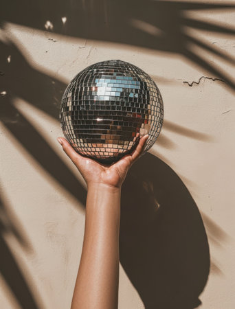 a hand holds a mirror ball in the shadow.の素材