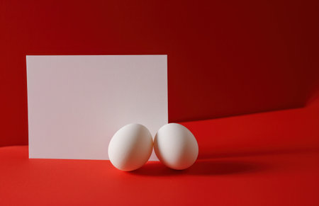 blank blank white card with red and white eggs on red background.の素材