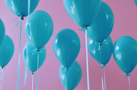 blue helium balloons suspended from a pink ceiling.の素材