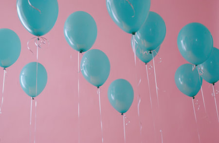 blue helium balloons suspended from a pink ceiling.の素材