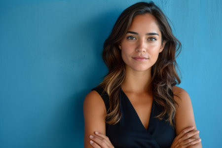 business woman with arms crossed against blue background.の素材