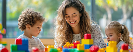 Three children happily build structures with colorful blocks alongside a smiling caregiver in a bright, playful environment. The atmosphere is lively and inspiring creativity.の素材