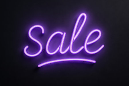 A vibrant purple neon sign reads sale, illuminating a dark background in a trendy retail shop. The atmosphere is inviting and calls attention to special deals..の素材