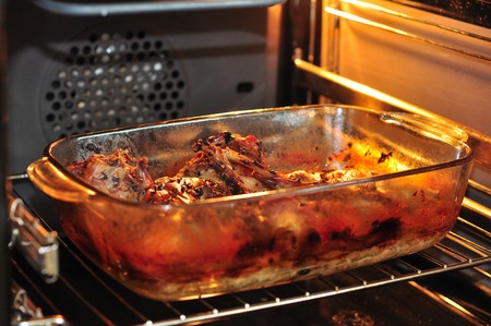 rabbit meat in roaster in tke oven with onion cumin and garlic on wooden vintage table