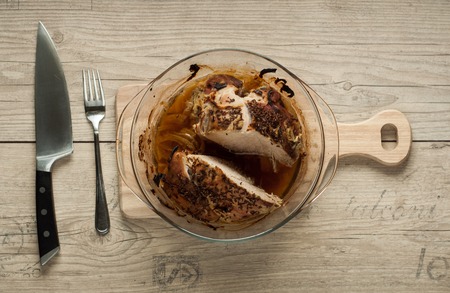 baked pork meat in roaster with onion cumin and garlic on wooden tableの写真素材