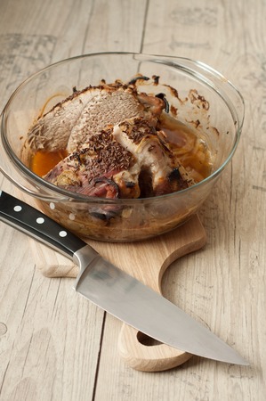 baked pork meat in roaster with onion cumin and garlic on wooden tableの写真素材