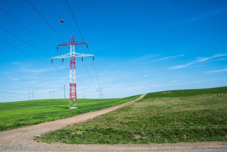 Electric pole in the center of the beautiful green fields, electric pylon, towerの写真素材