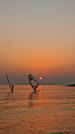 Sunrise in the sea with windsurfers on the waterの写真素材