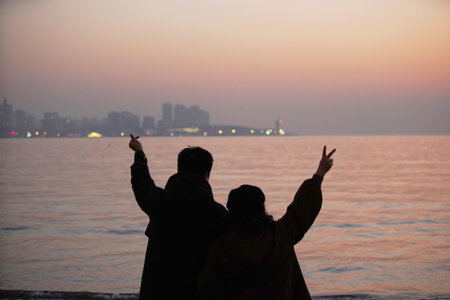 Couple watching the sunrise on the sea. Silhouette.の写真素材