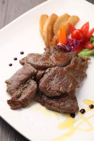 Grilled meat with potato wedges served on a plateの写真素材