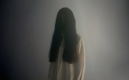 The blur faint  appearance of A ghostly silhouette of a white faceless Asian woman, long forested hair, hauntingly appearing. in a dense fogの写真素材