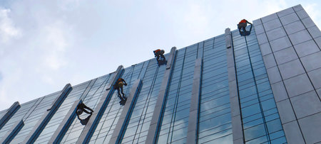 Employee cleaning the glass of a high-rise building city office Abseiling from the roof of a buildingの写真素材