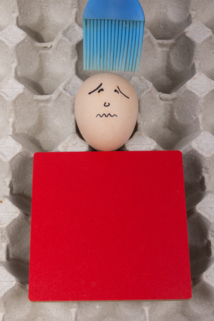 Cartoon face expression at egg and red board with finger also plastic brushの写真素材