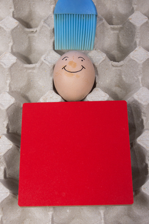 Cartoon face expression at egg and red board with finger also plastic brushの写真素材