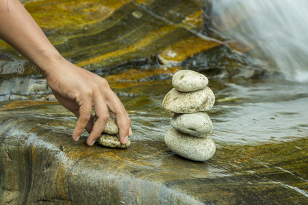 hands hold the rocks to set the backdrop of a waterfallの写真素材