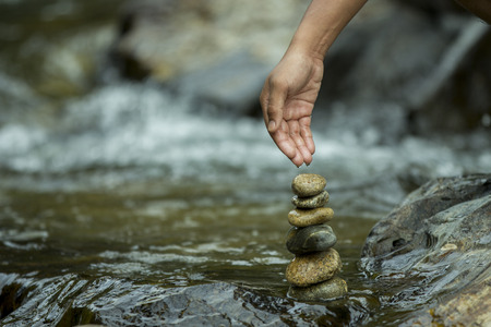 The hand drags water on the rocks on the backdrop of a waterfallの写真素材