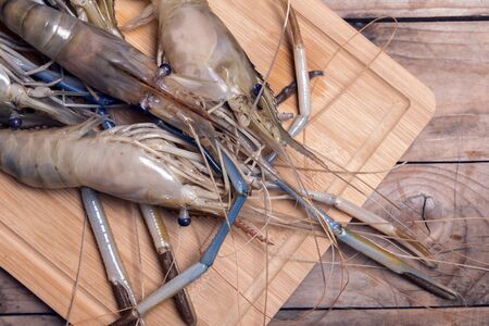 Big prawns on the wooden chopping board on the wooden tableの写真素材